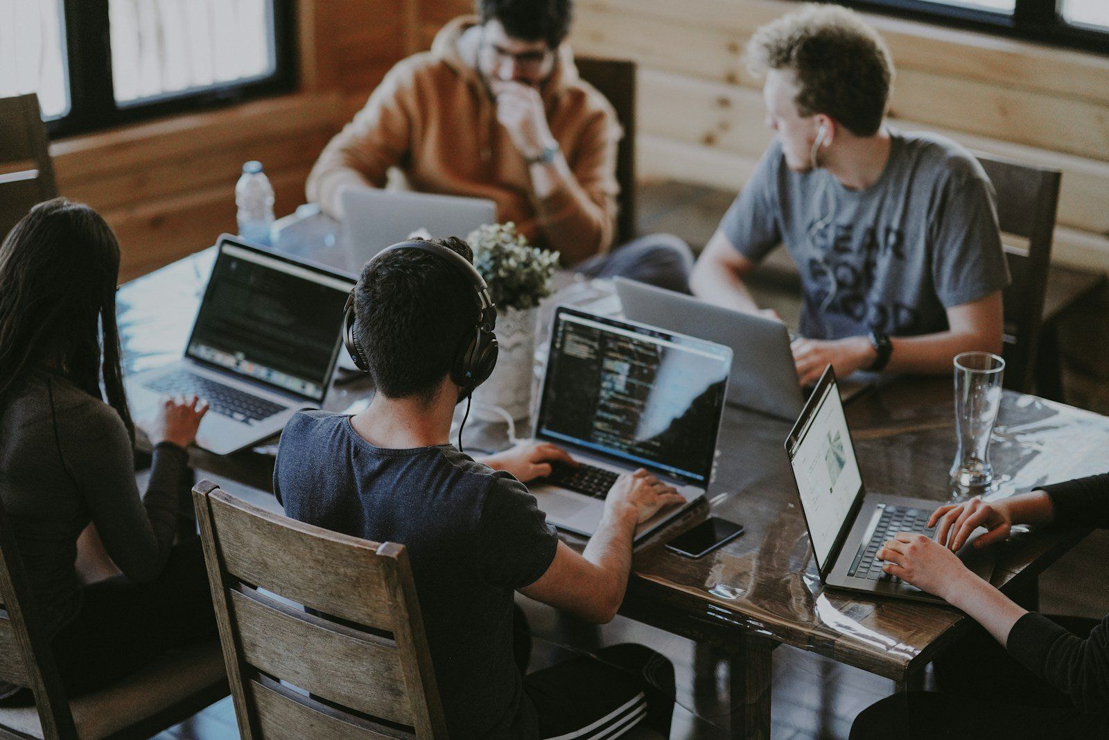 People working on laptops at a shared wooden table